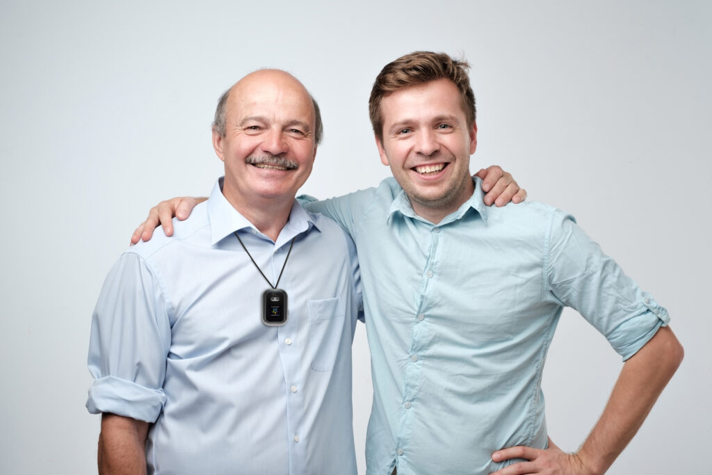 A senior man and young man smile as they have their arms around each other. 