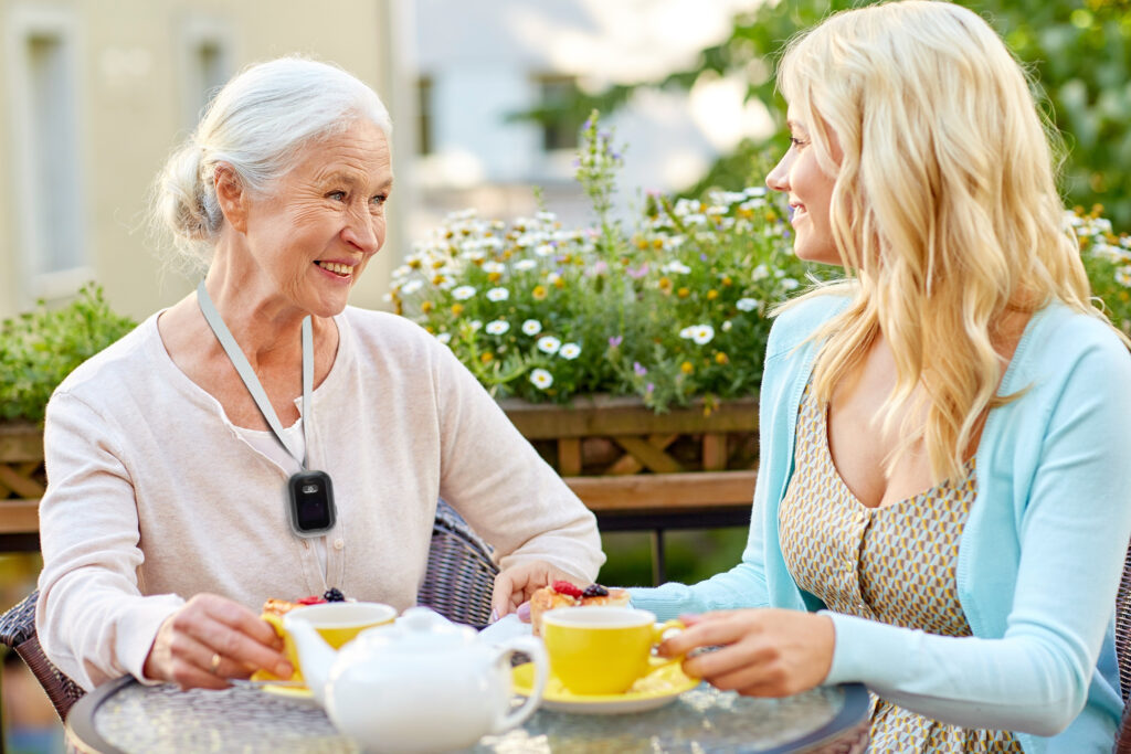 A senior woman and young woman enjoy tea together outside. 