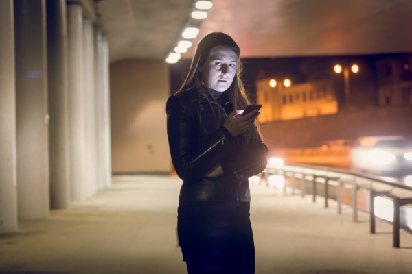A woman uses her safety alarm or app while outside at night. 