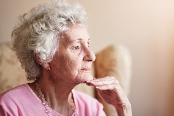 A senior woman looks pensive as she holds her hand to her chin.