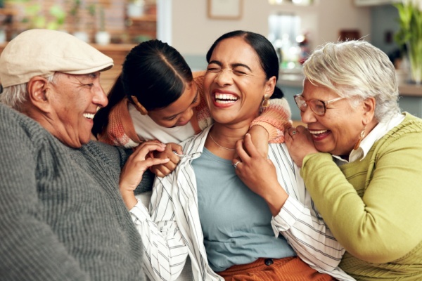 Generations of a family smile and laugh together on the couch.